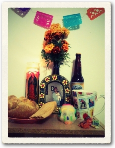 Altar with offering for Bertin Ventura, October 28th, 2012 (perforated paper decorations, Mexican marigolds, Virgin Mary candle, Mexican beer Victoria, chicken in green sauce tamale, sweet bread for the dead, sugar skull, assortment of Mexican candy, hot cornmeal and chocolate breakfast beverage, photograph in clay frame.) 